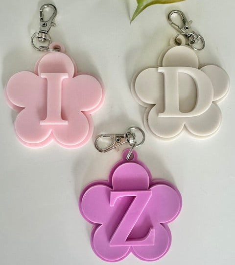 Three floral-shaped keychains with letters 'I', 'D', and 'Z' on a light background.