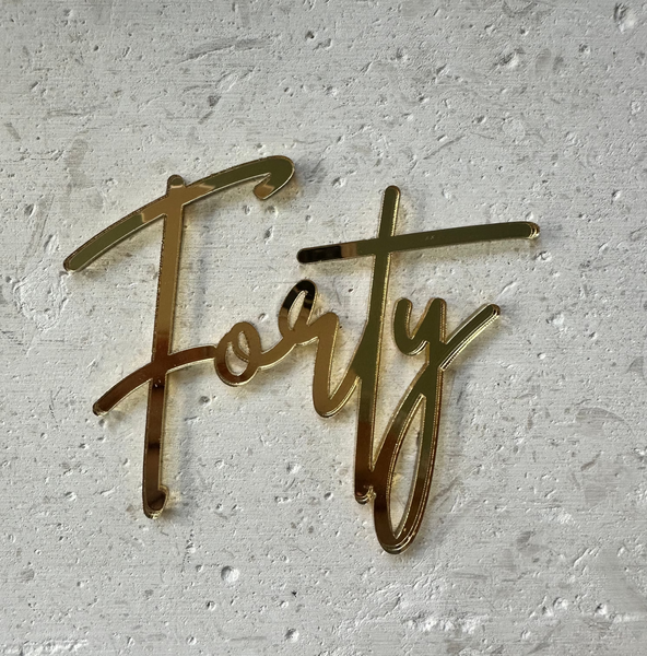 Gold metallic script wall sign spelling 'Forty' mounted on a textured white plaster wall.