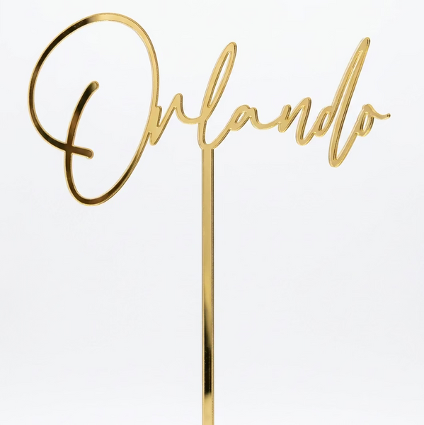 Gold script cake topper spelling 'Orlando' 