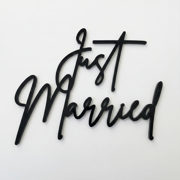 White script cake topper reading 'Just Married' on a light gray background.