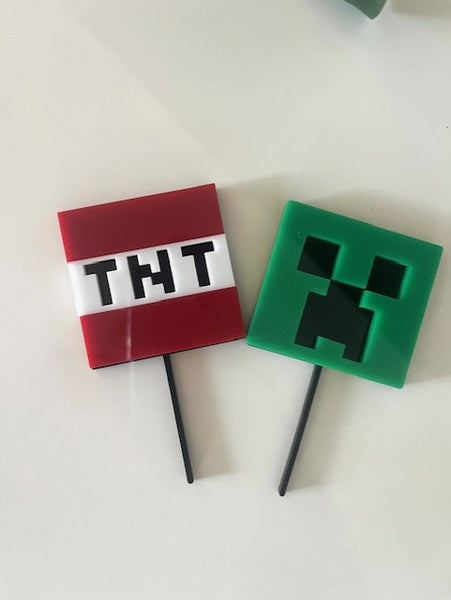 Two decorative picks, one with 'TNT' and the other with a green character, on a white background.