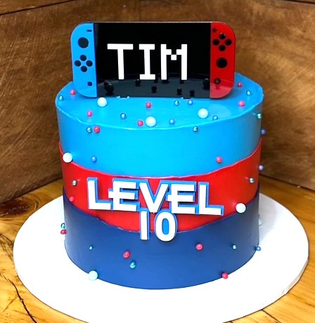 Cake designed like a Nintendo Switch with 'TIM' and 'LEVEL 10' text on a wooden background