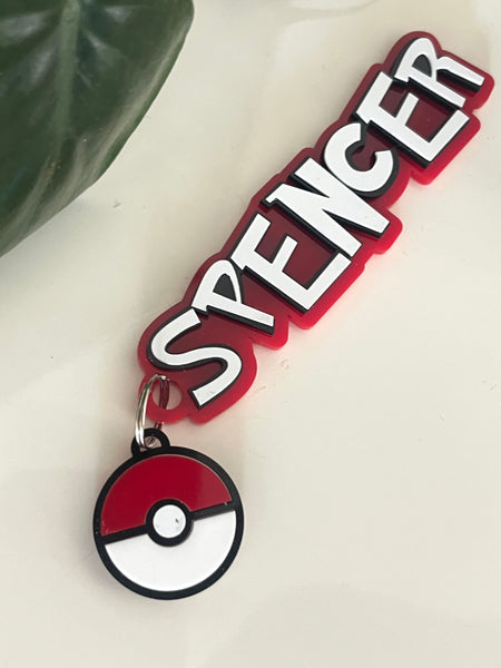 Keychain with 'SPENCER' text and Poké Ball design on a light background