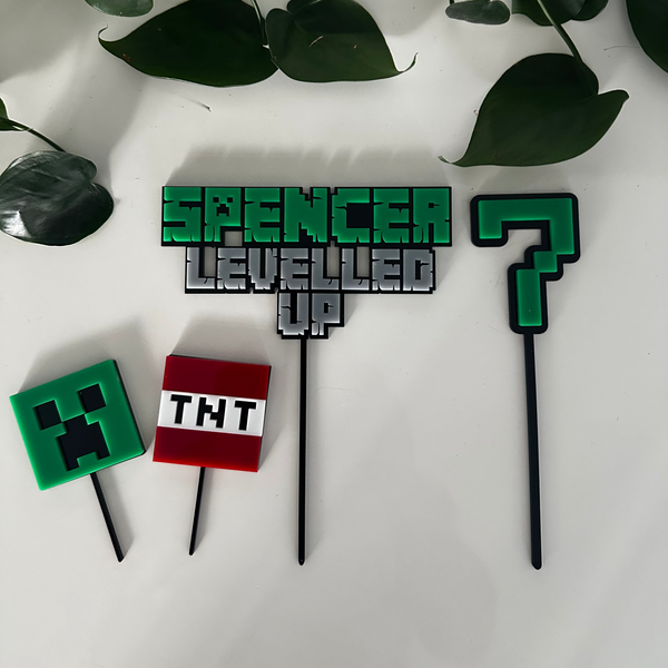 Set of Minecraft-themed cake toppers on a white surface with green leaves.