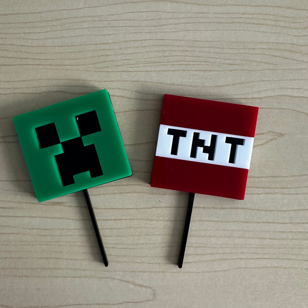 Two Minecraft-themed cake toppers on a wooden surface