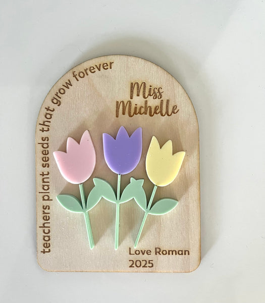 Wooden plaque with tulip-shaped pins and engraved text on a white background
