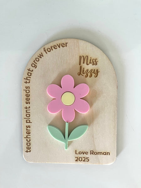 Wooden plaque with a pink flower and engraved text on a white background
