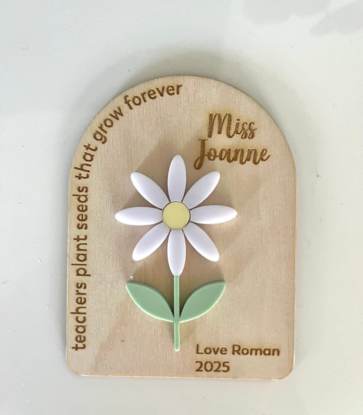 Wooden plaque with a daisy illustration and engraved text on a white background
