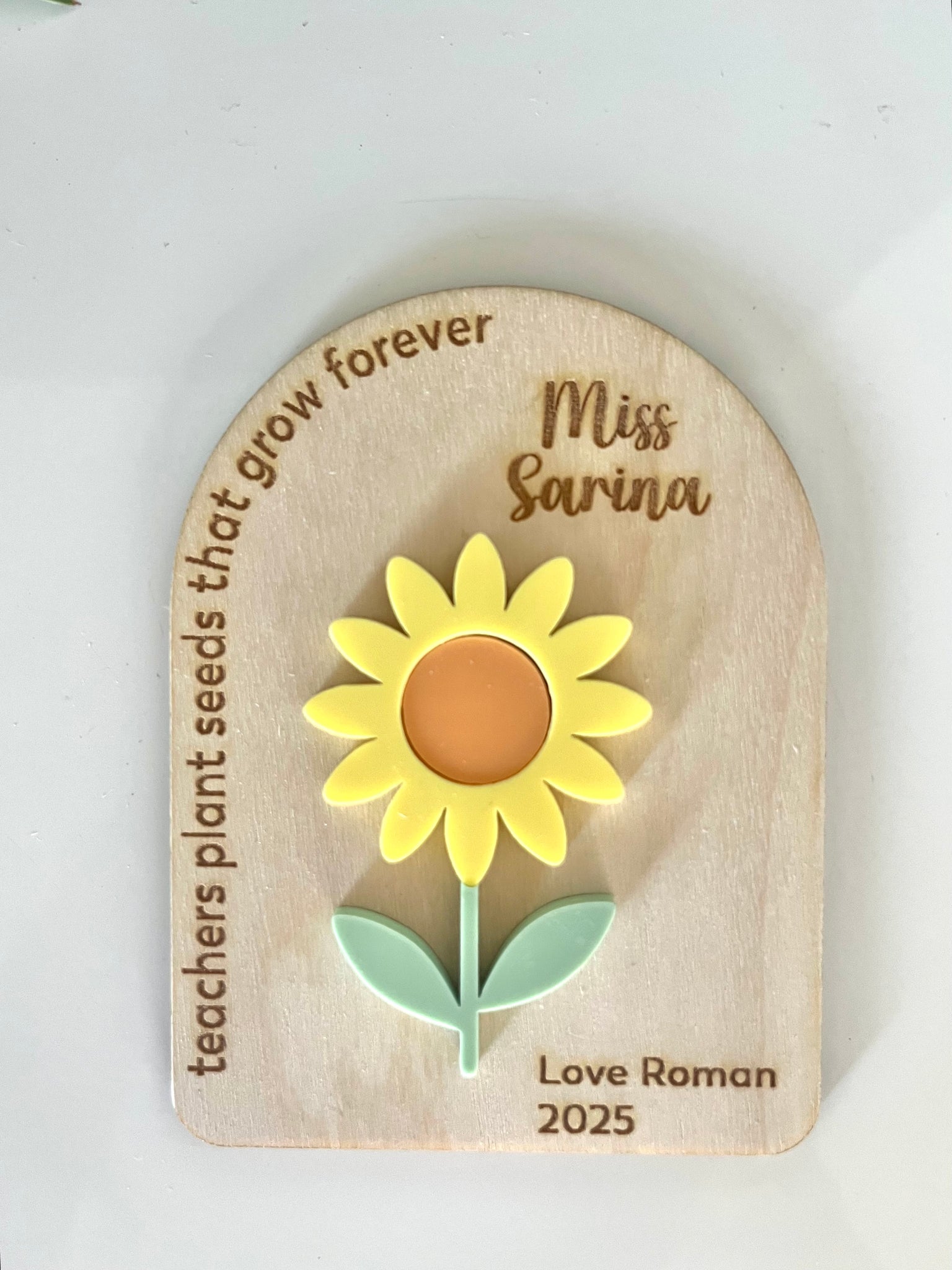 Wooden plaque with a sunflower design and engraved text on a white background